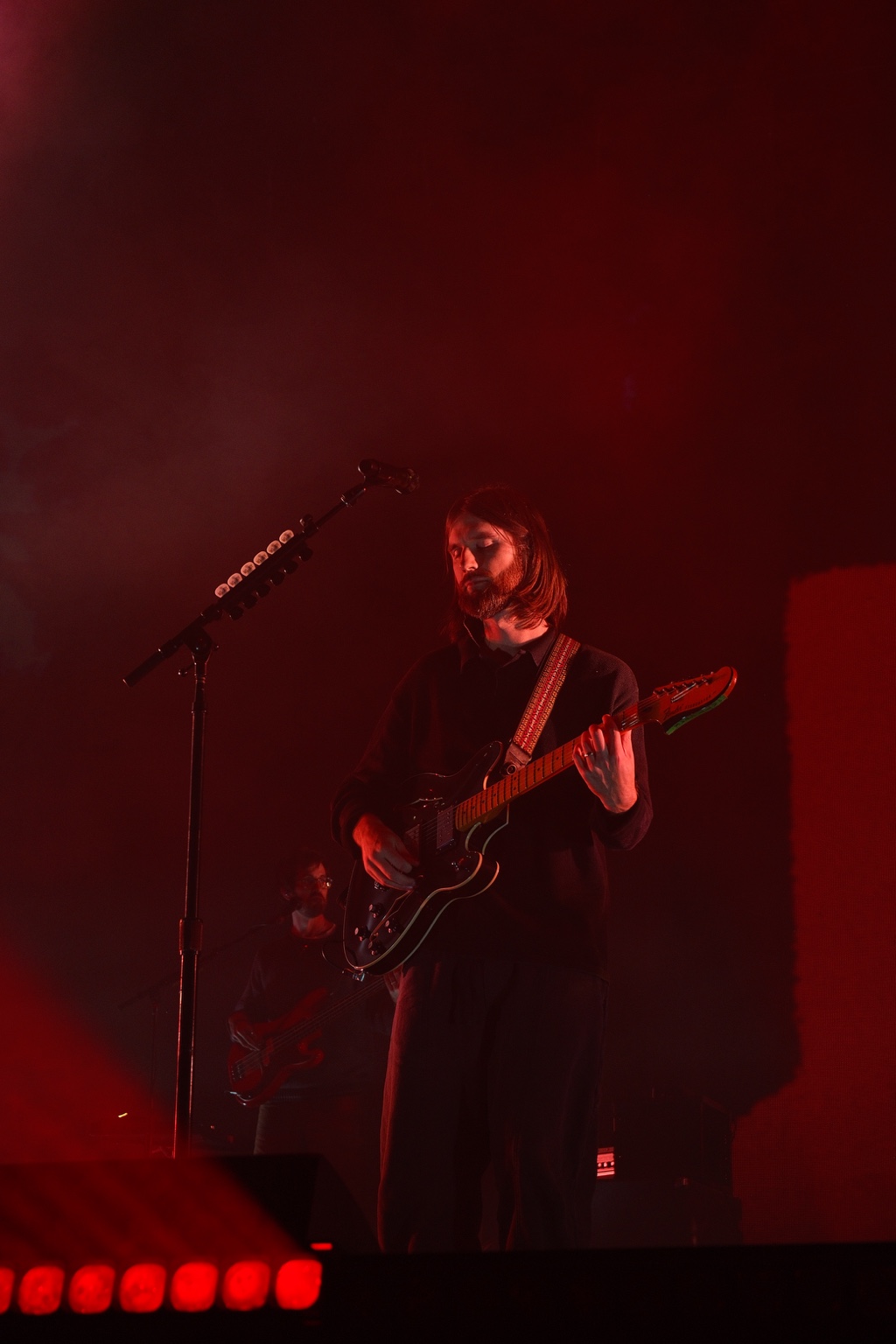 A guitarist plays beneath saturated red stage lights