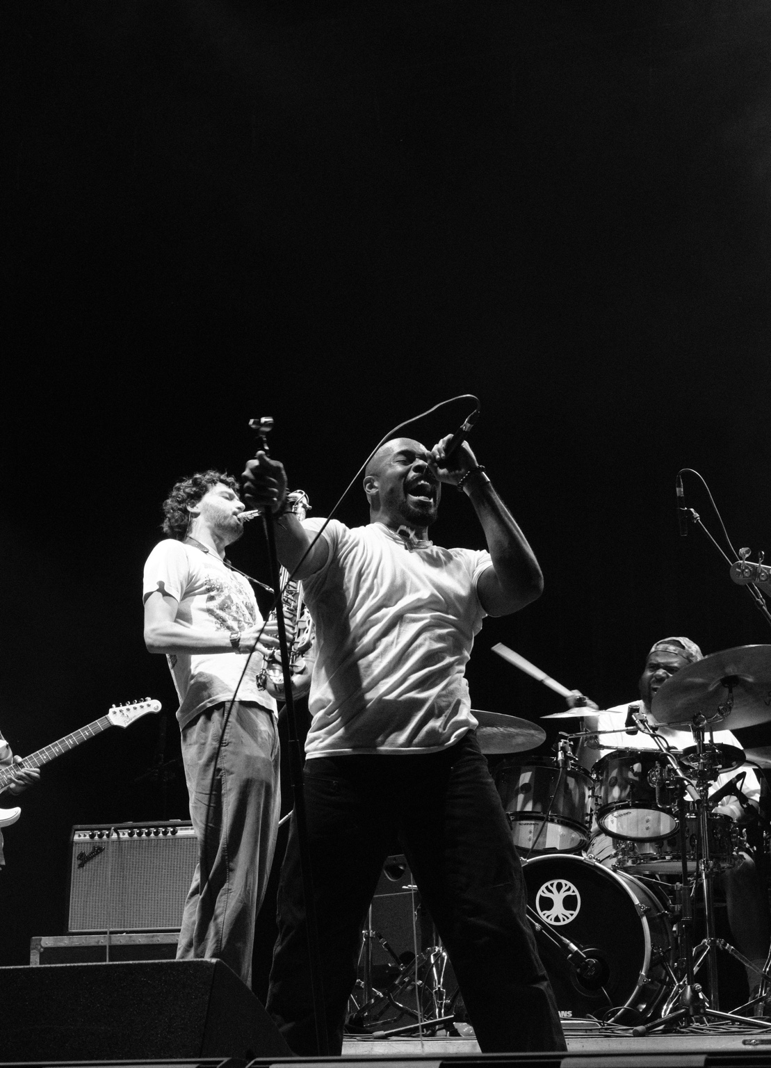 A vocalist sings beside a saxophonist and drummer