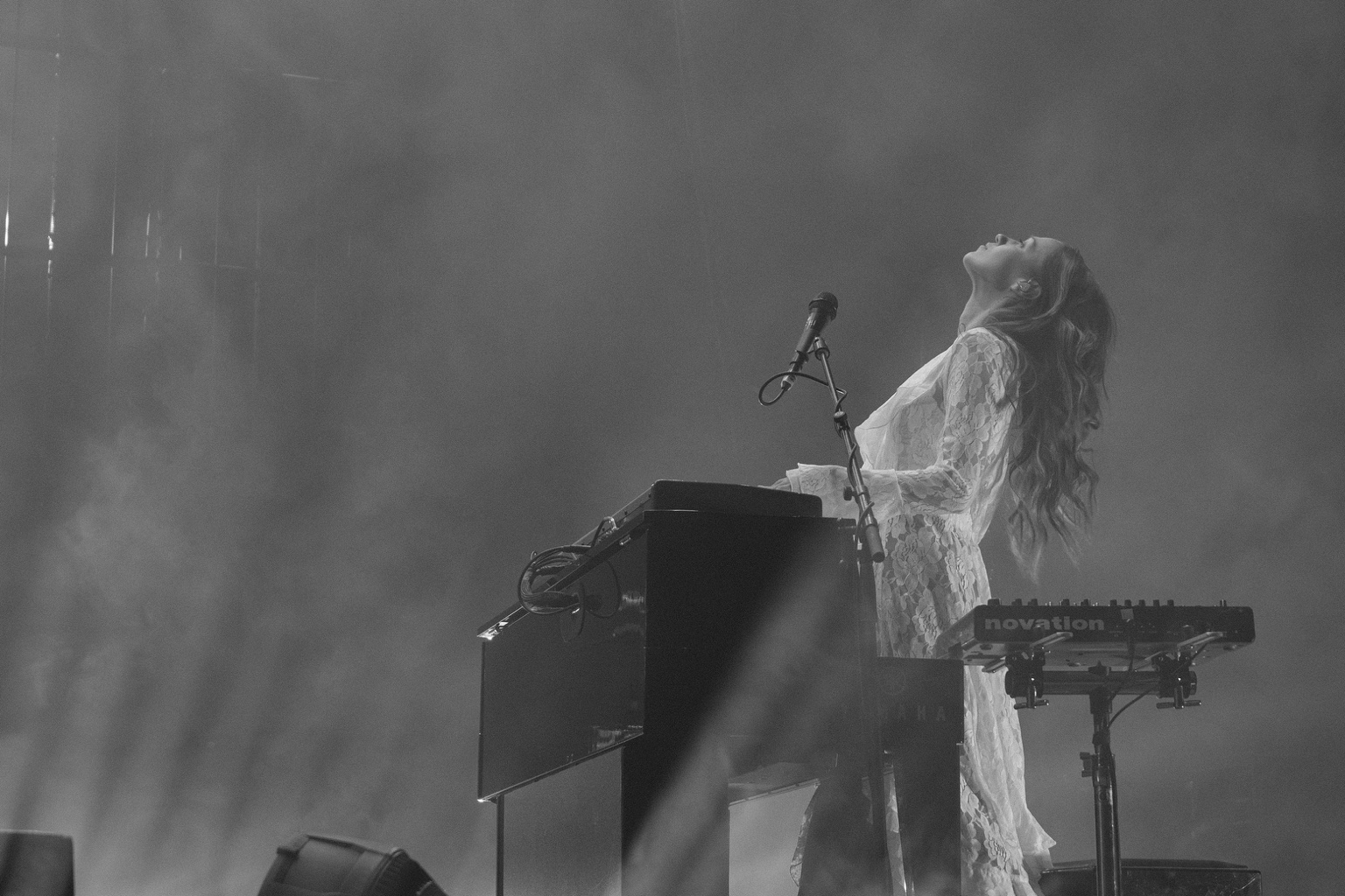 A keyboardist leans back into the stage light
