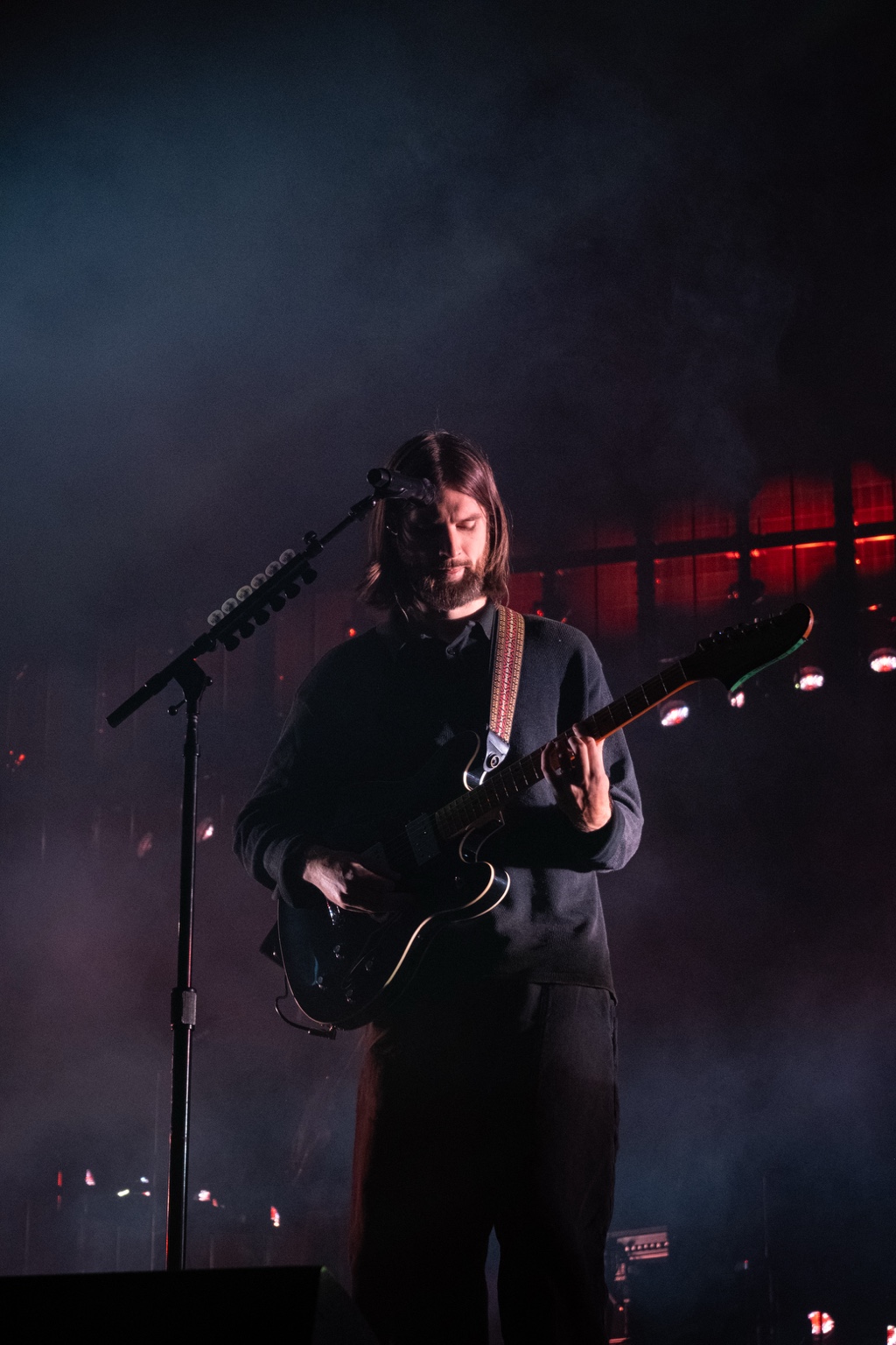 A guitarist plays amid blue haze and red lighting
