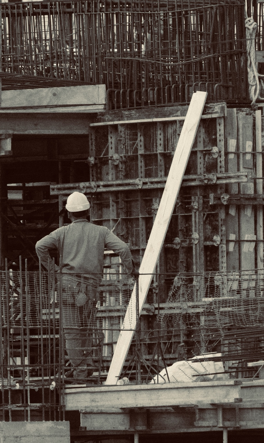 A construction worker stands among dense metal scaffolding