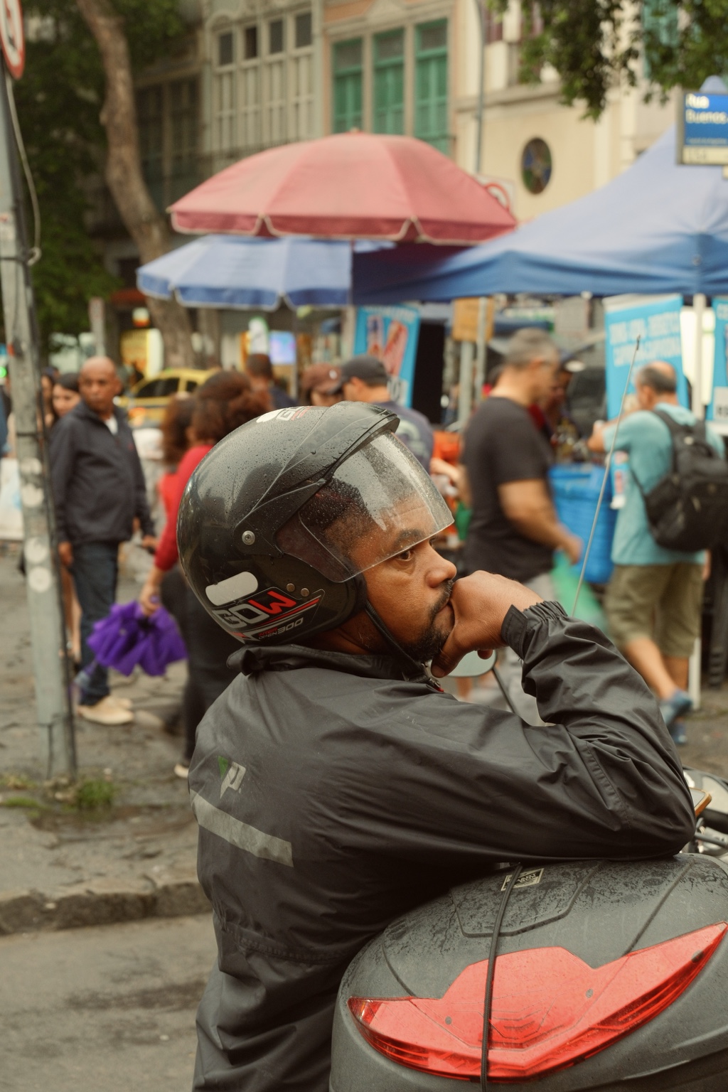 A helmeted rider pauses in a busy street market