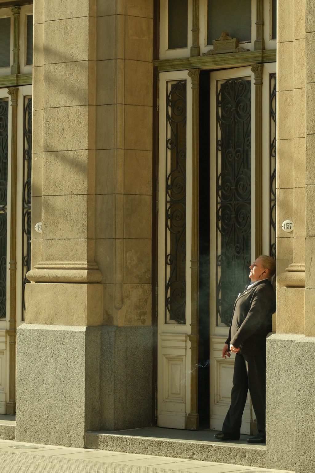A person stands in the shadow of a sunlit stone doorway